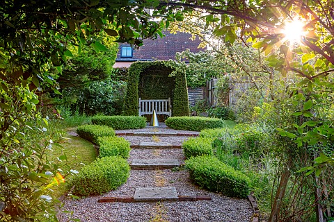 COTTAGE_ROW_DORSET_GRAVEL_PATH_TO_YEW_ARCH_WITH_WOODEN_SEAT_BENCH_BOX_HEDGING_WATER_FEATURE_GREEN_FO