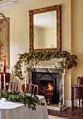 MARBURY HALL, SHROPSHIRE: DESIGNER SOFIE PATON-SMITH - DINING ROOM, FIREPLACE GARLAND OF HOPS, TABLE, CHAIRS, EUCALYPTUS TABLE DECORATION, CANDLES, MIRROR, DECEMBER
