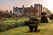HEVER CASTLE, KENT: MORNING LIGHT ON LAWN, TOPIARY YEW, DAFFODILS, CASTLE, NARCISSUS, MARCH, SPRING