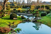LOWER BOWDEN MANOR, BERKSHIRE: SPRING, APRIL, POND, POOL, YEW BALLS, CLOUD PRUNED TREE IN WOODEN BOX, CONTAINER, BOULDERS, REFLECTIONS