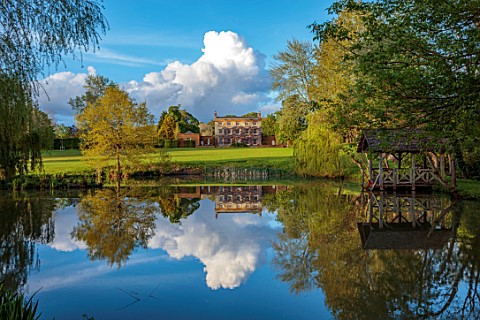 PRIORS_MARSTON_WARWICKSHIRE_VIEW_ACROSS_LAKE_POND_WATER_TO_HOUSE_SPRING_MAY_BOATHOUSE_BOAT_HOUSE_REF