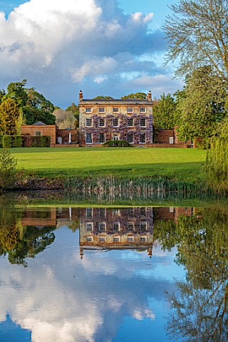 PRIORS_MARSTON_WARWICKSHIRE_VIEW_ACROSS_LAKE_POND_WATER_TO_HOUSE_SPRING_MAY_REFLECTIONS_REFLECTED_CL