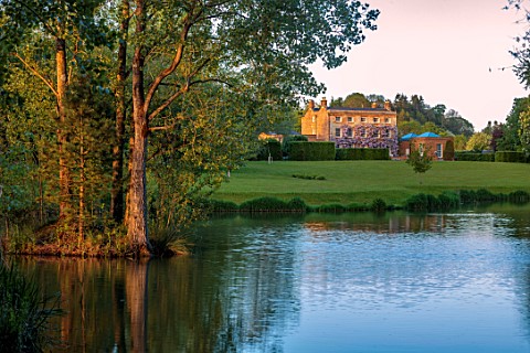 PRIORS_MARSTON_WARWICKSHIRE_TREES_MANOR_HOUSE_REFLECTED_IN_THE_WATER_POOL_LAKE_MAY_SPRING