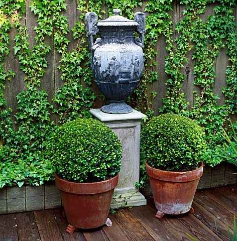 TWO_BOX_BALLS_FLANK_A_PEDESTAL_WITH_LEAD_URN_ON_DECKING_DESIGNER_CHRISTIAN_WRIGHT__SAN_FRANCISCO