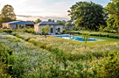 CHETTLE, DORSET: THE SWIMMING POOL AND POOL HOUSE  WITH WILDFLOWER MEADOW OF OXE- EYE DAISIES, JUNE, SUMMER, MEADOWS, WILDFLOWERS