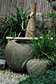 BAMBOO WATER PUMP EMPTIES INTO STONE URN IN THE JAPANESE GARDEN AT THE HUNTINGTON BOTANICAL GARDENS  CALIFORNIA