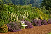 EASTON WALLED GARDENS, LINCOLNSHIRE: LARGE HERBACEOUS BORDER BESIDE GRAVEL PATH WITH NEPETA, LONG BORDER, CATMINT, COUNTRY GARDEN, CLASSIC, WHITE METAL SEAT, BENCH