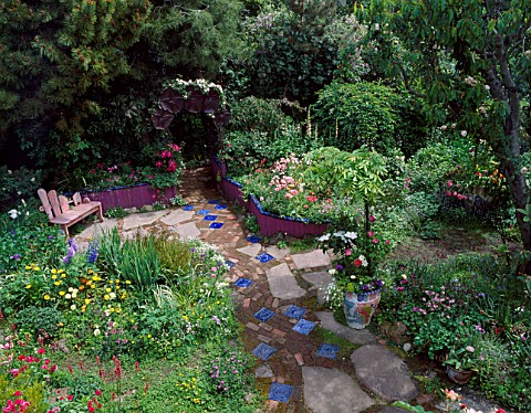 LOOKING_DOWN_ON_GARDEN_PATH_WITH_INSET_BLUE_TILES_LEADS_TO_WOODEN_SEAT__RAISED_BEDS_DESKEEYLA_MEADOW