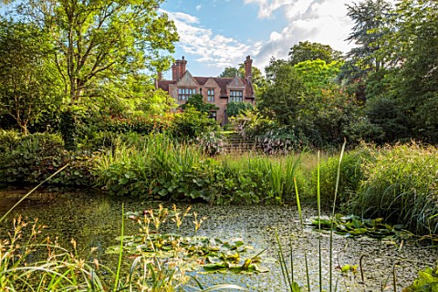 STOCKCROSS_HOUSE_HAMPSHIRE_VIEW_OF_HOUSE_ACROSS_POND_WITH_STEPS_SUMMER_AUGUST_WATER_POOL_TREES