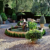 STONE ELEPHANT FOUNTAIN STANDS IN CIRCULAR POOL IN THE PEBBLED COURTYARD.LA CASELLA FRANCE.DESIGN:CLAUS SCHEINERT