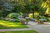 BOWCLIFFE HALL, YORKSHIRE: DESIGN ALISTAIR BALDWIN: GRAVEL PATH, STONE WALLS, MAPLE, STONE URNS, CONTAINERA, WOODEN BENCH, SEAT, MISCANTHUS MORNING LIGHT, COTINUS, SEPTEMBER