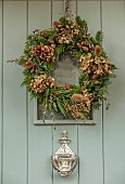 PEAR TREE COTTAGE, OXFORDSHIRE: FRONT DOOR WREATH, CHRISTMAS, CYPRESS, DRIED HYDRANGEA HEADS, TEASELS, FOLIAGE