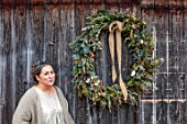 CEST TOUT INTERIORS: THE BARN SHOP, KATHRYN MCFALL, FOUNDER OF CEST TOUT INTERIORS OUTSIDE THE BARN SHOP WITH LARGE FOLIAGEWREATH, FIR, EUCALYPTUS, CYPRESS, LICHENED TWIGS