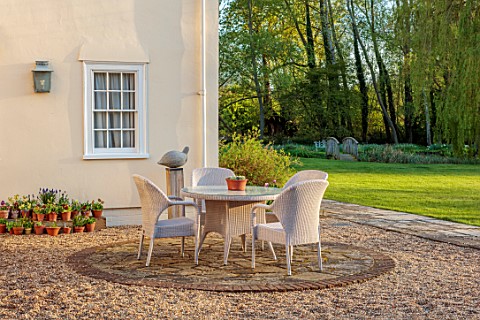 ULTING_WICK_ESSEX_PATIO_BESIDE_HOUSE_WITH_TABLE_CHAIRS_AURICULAS_BY_HOUSE_SPRING_APRIL