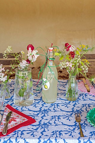 HAM_COURT_OXFORDSHIRE_WILLOW_CROSSLEY_WORKHOP__FLOWERS_IN_GLASS_BOTTLES_VASES_ON_TABLE