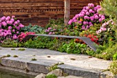 CHELSEA 2022: A SWISS SANCTUARY BY LILLY GOMM: RHODODENDRONS, METAL SEAT, POOL, POND, WATER, STONES, PAVING