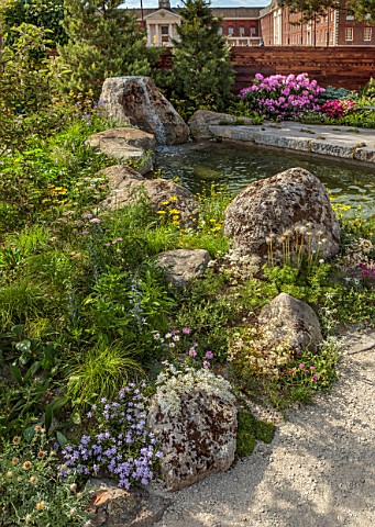 CHELSEA_2022_A_SWISS_SANCTUARY_BY_LILLY_GOMM_METAL_SEAT_BENCH_RHODODENDRONS_GRAVEL_PATHS_ROCKS_WATER