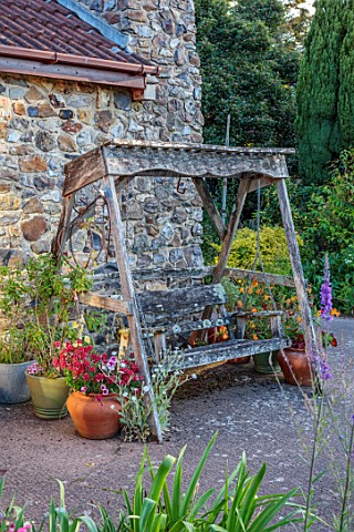 LITTLE_ASH_BUNGALOW_DEVON_WOODEN_BENCH_SWING_SEAT_BESIDE_HOUSE_CONTAINERS