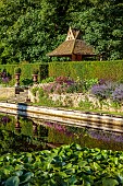 THE SUMMERHOUSE, OXFORDSHIRE: JULY, SUMMER, CANAL, POND, POOL, WATER, GARDEN, BORDERS, TREES, WATERLILIES, STONE, DOVECOTE, STEPS, URNS, CONTAINERS, COTSWOLDS