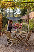 THE LAUNDRY GARDEN, DENBIGH, WALES: NOVEMBER, AUTUMN, FALL, WALLED GARDEN, PATH, WOODEN TABLE, CHAIRS, DAHLIAS, CONTAINER, PLANE TREE, JENNY WILLIAMS