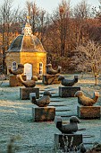 ROCKCLIFFE GARDEN, GLOUCESTERSHIRE: CLIPPED TOPIARY YEW BIRDS, DOVECOTE, BUILDING, ORCHARD, FROST, FROSTY, SUNRISE