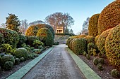 BRODSWORTH HALL, YORKSHIRE: DAWN, SUNRISE, WINTER, JANUARY, FROST, CLIPPED TOPIARY SHRUBS, HEDGES, HEDGING, EVERGREENS, VICTORIAN, PATHS, BORDERS, FORMAL, GARDEN, STONE SUMMERHOUSE