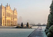 BRODSWORTH HALL, YORKSHIRE: DAWN, SUNRISE, WINTER, JANUARY, FROST, CLIPPED TOPIARY SHRUBS, HEDGES, HEDGING, EVERGREENS, VICTORIAN, PATHS, BORDERS, FORMAL, GARDEN, MIST, FOG