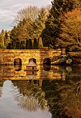 THENFORD GARDENS & ARBORETUM, NORTHAMPTONSHIRE: LAKE, BRIDGE AND THE RILL BEYOND IN FEBRUARY, TREES, WATER, LAKE, WINTER, GIANT GUNNERA SCULPTURE, DUCK HOUSE, REFLECTIONS