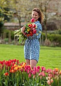 BROWN FLOWERS, OXFORDSHIRE: ANNA BROWN HOLDING TULIPS IN HER FIELD, SPRING, APRIL
