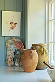 PRIVATE GARDEN, DEDHAM VALE, SUFFOLK: KITCHEN BY LOCAL COMPANY CHURCHILL BROTHERS, CERULLIAN BLUE, EDWARD BULMER, FRENCH OLIVE JARS BESIDE ARTISTS PALETTE, PAINTING BY LUCY PASS