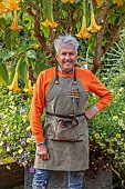 EAST RUSTON OLD VICARAGE GARDEN, NORFOLK: ALAN GRAY STANDS IN THE DUTCH GARDEN BENEATH A LARGE YELLOW BRUGMANSIA IN A CONTAINER