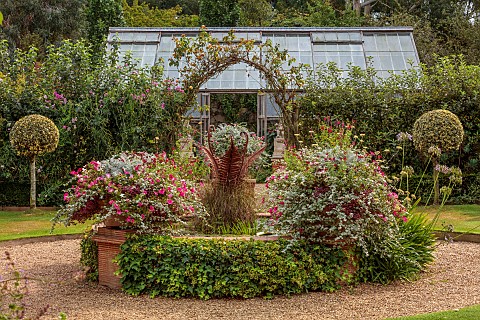 EAST_RUSTON_OLD_VICARAGE_GARDEN_NORFOLK_GLASSHOUSE_GARDEN_CIRCULAR_POND_WATER_POOL_URNS_PLANTED_WITH