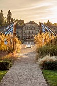 GRANTLEY HALL, YORKSHIRE: SUNSET, GRAVEL GARDEN, PATINATED STEEL AND COLOURED STAINLESS STEEL GLAZED CUPOLA SEAT AT END OF RILL, BORDERS, GRASSES, SEPTEMBER