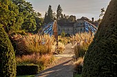GRANTLEY HALL, YORKSHIRE: SUNSET, GRAVEL GARDEN, PATINATED STEEL AND COLOURED STAINLESS STEEL GLAZED CUPOLA SEAT AT END OF RILL, BORDERS, GRASSES, SEPTEMBER