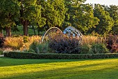GRANTLEY HALL, YORKSHIRE: SUNSET, LAWN, BORDERS, GRASSES, PATINATED STEEL AND COLOURED STAINLESS STEEL GLAZED CUPOLA SEAT, SEPTEMBER