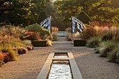 GRANTLEY HALL, YORKSHIRE: LIGHTING, DAWN, BOX EDGED BEDS, WATER, POOL, PATINATED STEEL AND COLOURED STAINLESS STEEL GLAZED CUPOLA SEAT, RILL, WATER, BORDERS, GRASSES, SEPTEMBER