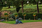 GRANTLEY HALL, YORKSHIRE: LIGHTING, LION STATUE BY PATH, DRIVE, LOLLIPOP TOPIARY, YEW HEDGES, HEDGING, BORROWED LANDSCAPE, COWS
