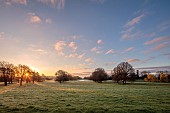 COTTESBROOKE HALL AND GARDENS, NORTHAMPTONSHIRE: VIEW FROM SOUTH TERRACE OVER LAKE TO BRIXWORTH CHURCH, SUNRISE, MARCH, SPRING, BORROWED LANDSCAPE