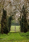 COLUMBINE HALL, SUFFOLK: VIEW ALONG GRASS PATH TO STATUE AND COUNTRYSIDE BEYOND, TREES, MARCH
