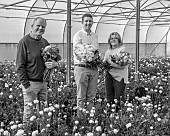 SMITH & MUNSON, LINCOLNSHIRE: BLACK AND WHITE PHOTO OF JO, ED AND STEPHEN MUNSON HOLDING RANUNCULUS IN A GREENHOUSE