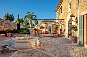 PRIVATE GARDEN ALARO, MALLORCA, DESIGNED BY MASHAMBA DESIGN: TERRACE AT BACK OF VILLA, COURTYARD, FOUNTAIN, PALM TREE, COBBLES, PATIO