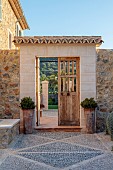 PRIVATE GARDEN ALARO, MALLORCA, DESIGNED BY MASHAMBA DESIGN: ENTRANCE TO COURTYARD, WALL, GATE, TERRACOTTA CONTAINERS, DECORATIVE CONBBLED FLOOR