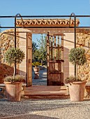 PRIVATE GARDEN ALARO, MALLORCA, DESIGNED BY MASHAMBA DESIGN: ENTRANCE TO COURTYARD, WALL, GATE, TERRACOTTA CONTAINERS, DECORATIVE COBBLED FLOOR