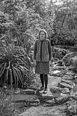 DODDINGTON PLACE, KENT: BLACK AND WHITE PHOTOGRAPH OF OWNER AMICIA OLDFIELD IN THE ROCK GARDEN, APRIL, SPRING