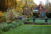 DODDINGTON PLACE, KENT: LAWN AND BORDER BESIDE THE SUNKEN GARDEN. COPPER CONTAINERS PLANTED WITH WHITE TULIPS, SILVER AND WHITE BORDER, LAWN