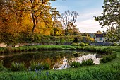 CAISSON GARDEN, SOMERSET: ROUND POND AND TOPIARY MEADOW IN FRONT OF THE HOUSE, APRIL, SPRING, WATER, POOL, CLIPPED BOX BALLS