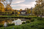 CAISSON GARDEN, SOMERSET: ROUND POND AND TOPIARY MEADOW IN FRONT OF THE HOUSE, APRIL, SPRING, WATER, POOL, CLIPPED BOX BALLS