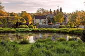 CAISSON GARDEN, SOMERSET: ROUND POND AND TOPIARY MEADOW IN FRONT OF THE HOUSE, APRIL, SPRING, WATER, POOL, CLIPPED BOX BALLS