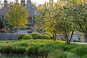 CAISSON GARDEN, SOMERSET: ROUND POND AND TOPIARY MEADOW IN FRONT OF THE HOUSE, APRIL, SPRING, WATER, POOL, CLIPPED BOX BALLS