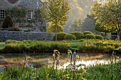CAISSON GARDEN, SOMERSET: ROUND POND AND TOPIARY MEADOW IN FRONT OF THE HOUSE, APRIL, SPRING, WATER, POOL, CLIPPED BOX BALLS